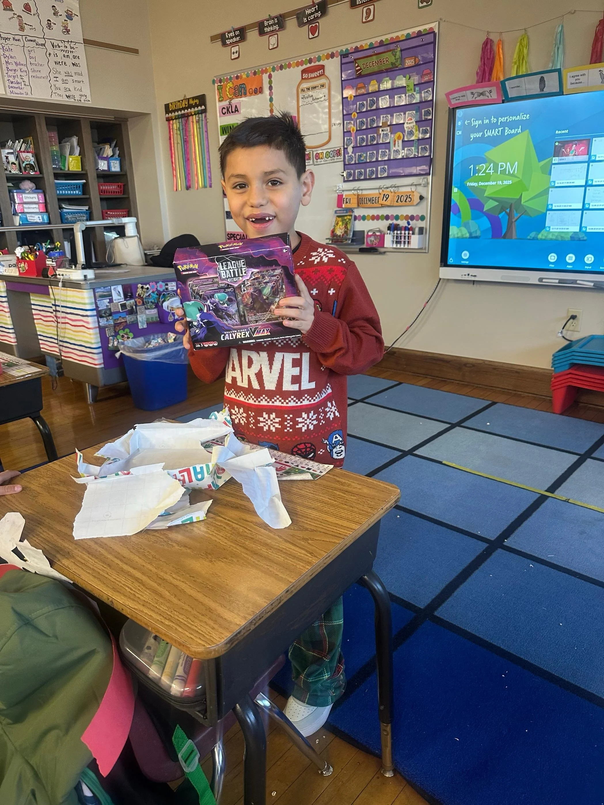 Second grade student opening a pack of Pokémon cards as part of the Advent Angels program at St. Anthony School—capturing joyful student engagement, seasonal giving, and a supportive faith-based community in Milwaukee, WI.