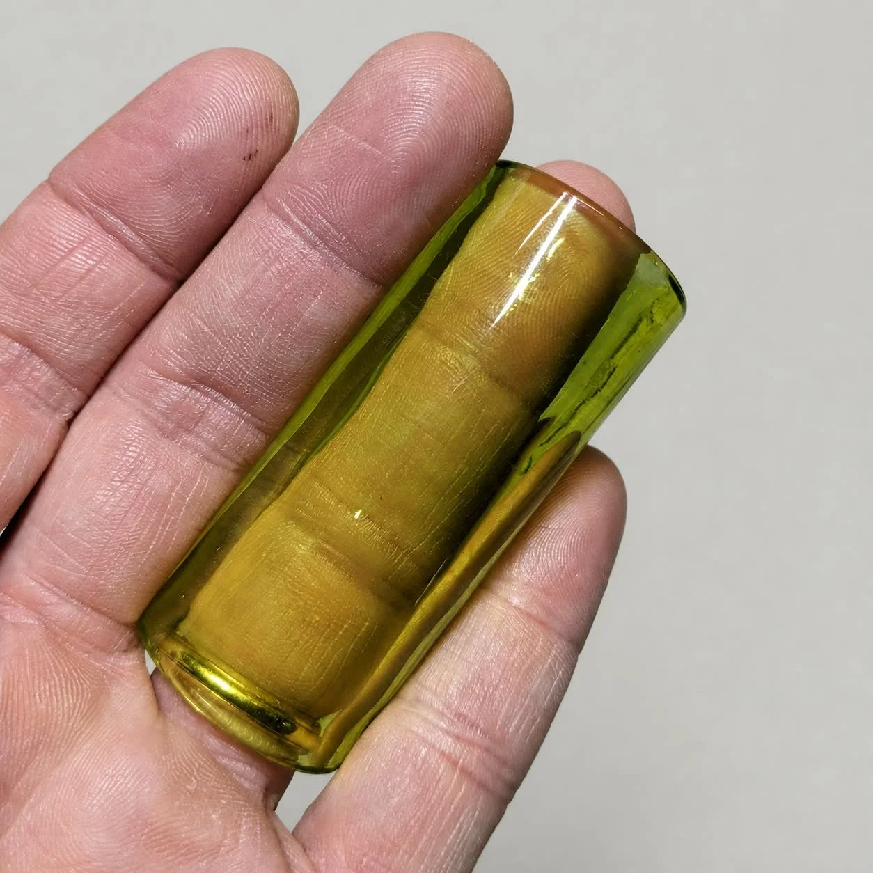 Blacklight Glow #2 non-tapered glass guitar slide shown in its yellow amber natural-light color