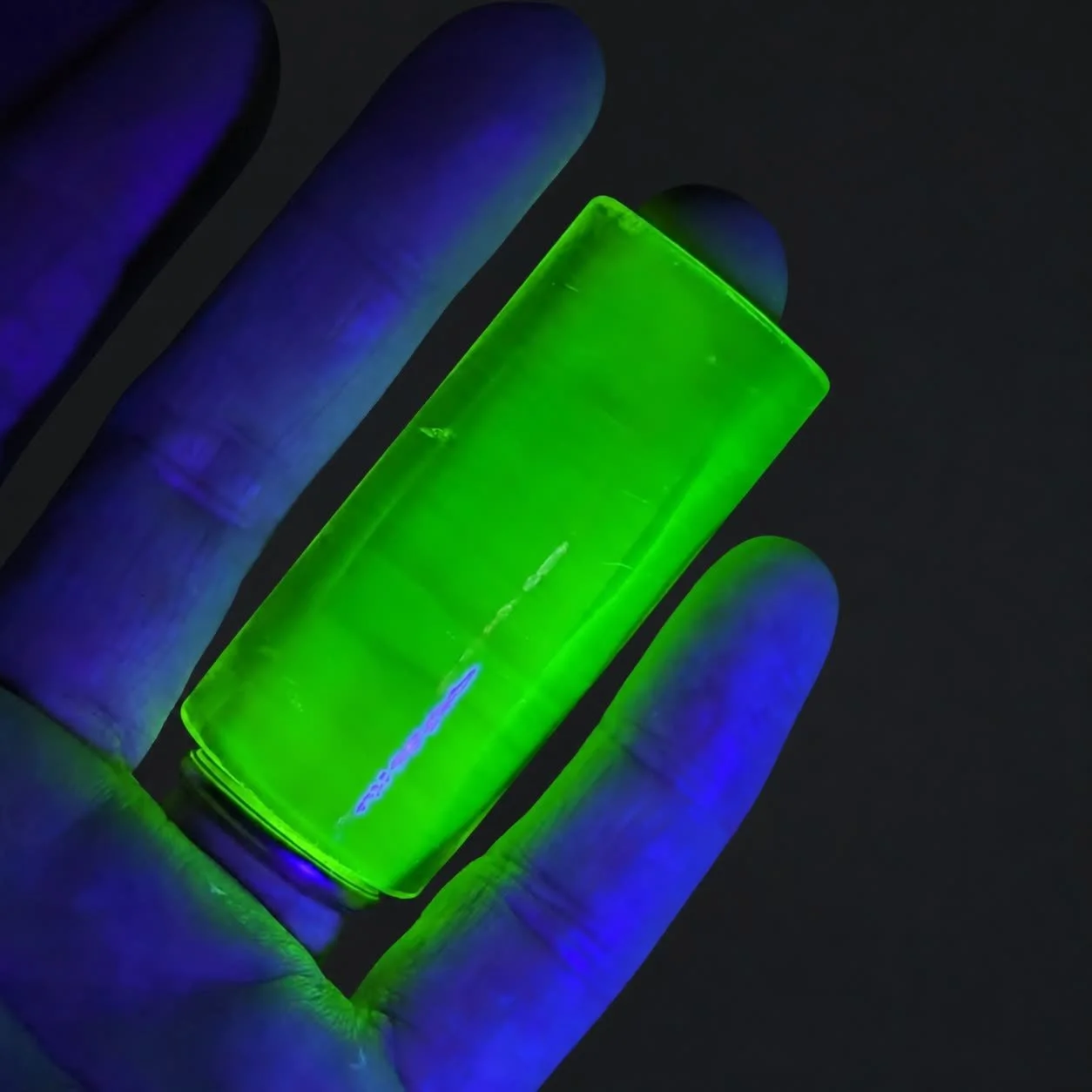Blacklight Glow #2 UV-reactive glass guitar slide fluorescing neon green under black light in hand
