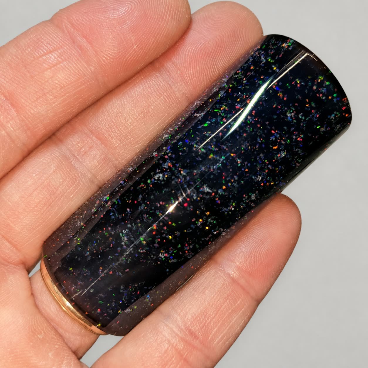 Reverse-side close-up of Crushed Opal #1 black glass guitar slide with encased synthetic opal