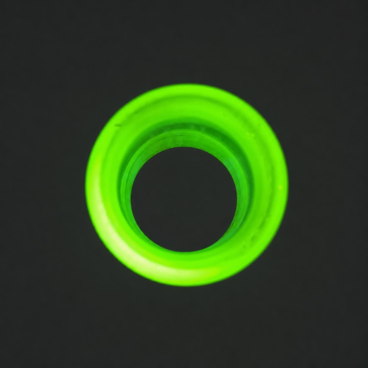 End view of Blacklight Glow #1 non-tapered glass guitar slide fluorescing under UV light