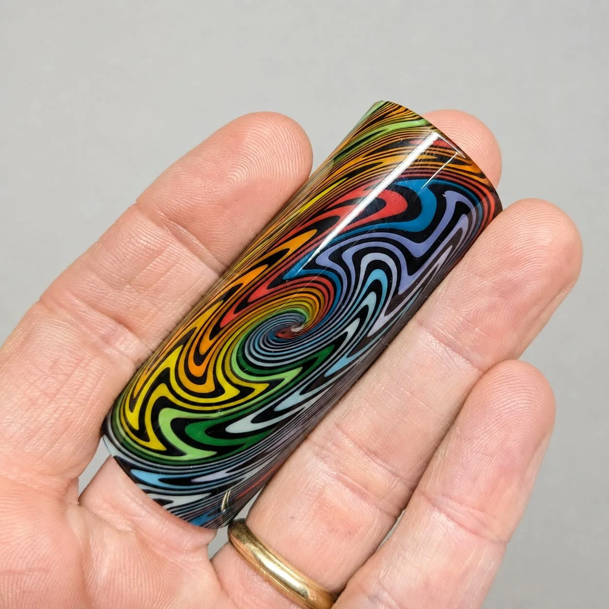 Rainbow Spiral handmade glass guitar slide with multicolor wig-wag spiral pattern resting on hand