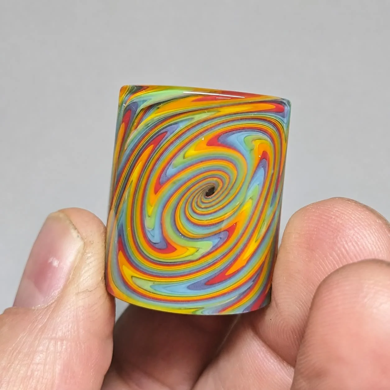 Reverse spiral view of Tie Dye Spiral Mini glass guitar slide with yellow, orange, red, green, blue, and lavender pattern