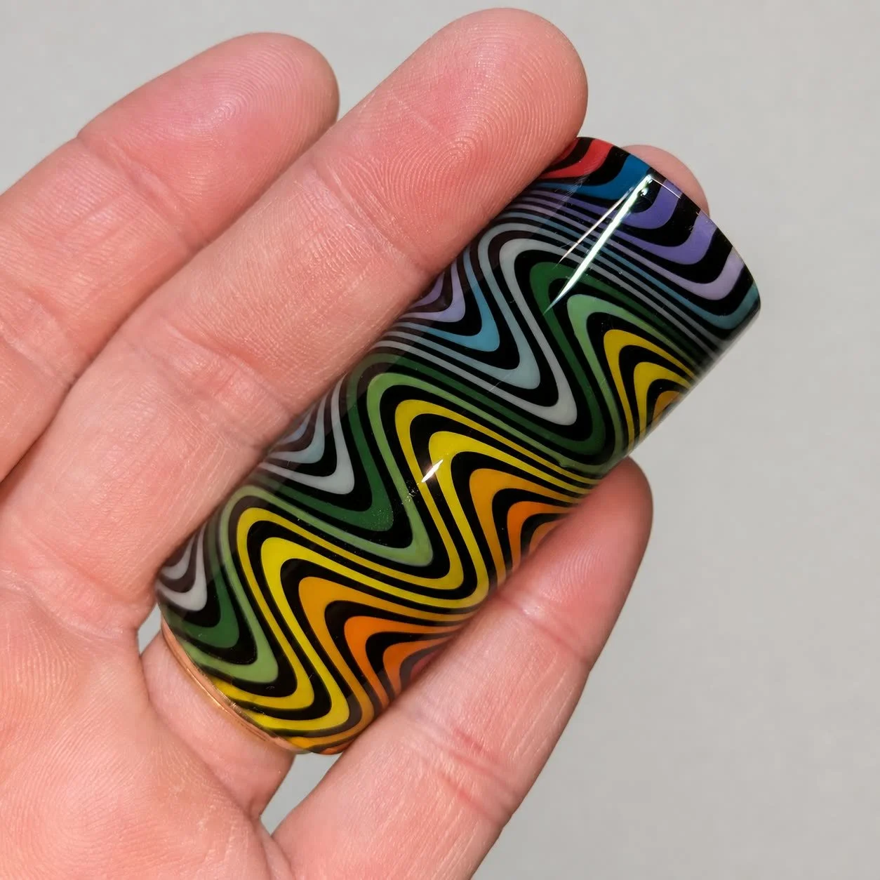 Rainbow Wig Wag handmade glass guitar slide with multicolor bent-line pattern shown in hand