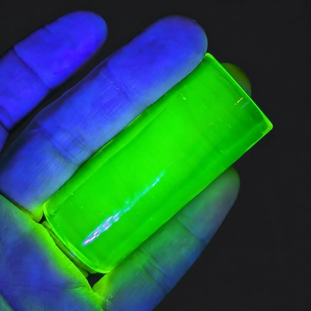 Blacklight Glow #1 UV-reactive glass guitar slide fluorescing neon green under black light in hand