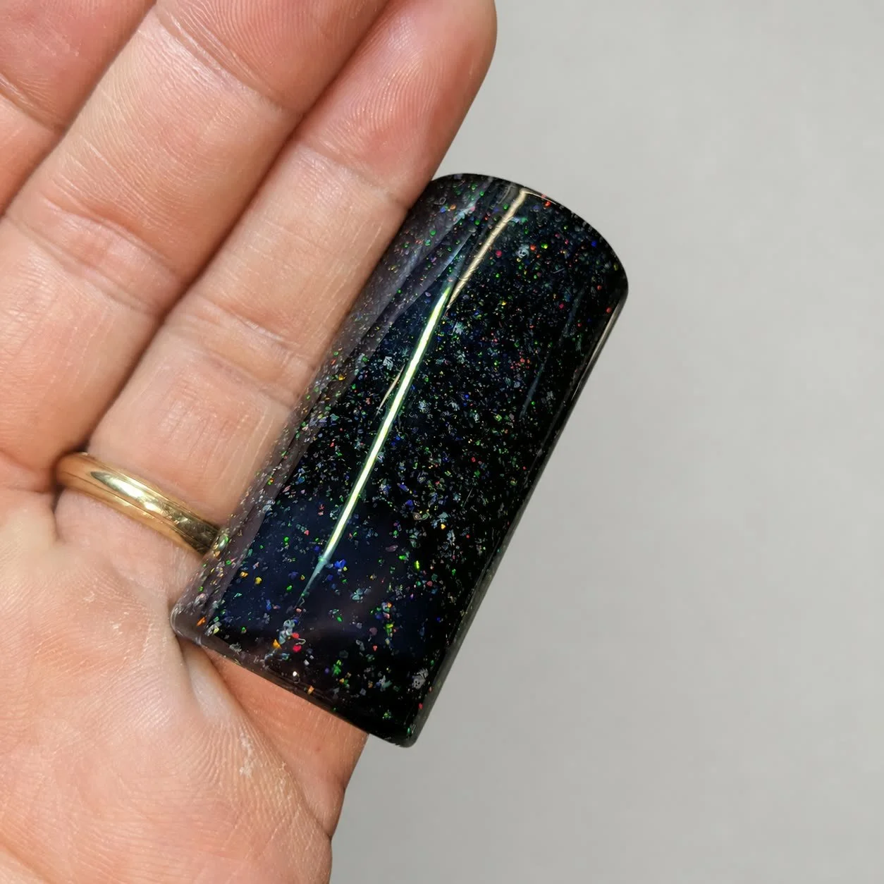 Reverse-side close-up of Crushed Opal #2 black glass guitar slide with encased synthetic opal