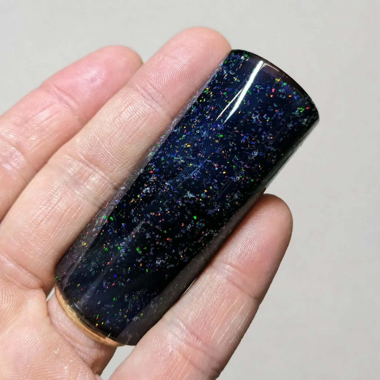 Crushed Opal #1 handmade black glass guitar slide with multicolor synthetic opal shown in hand