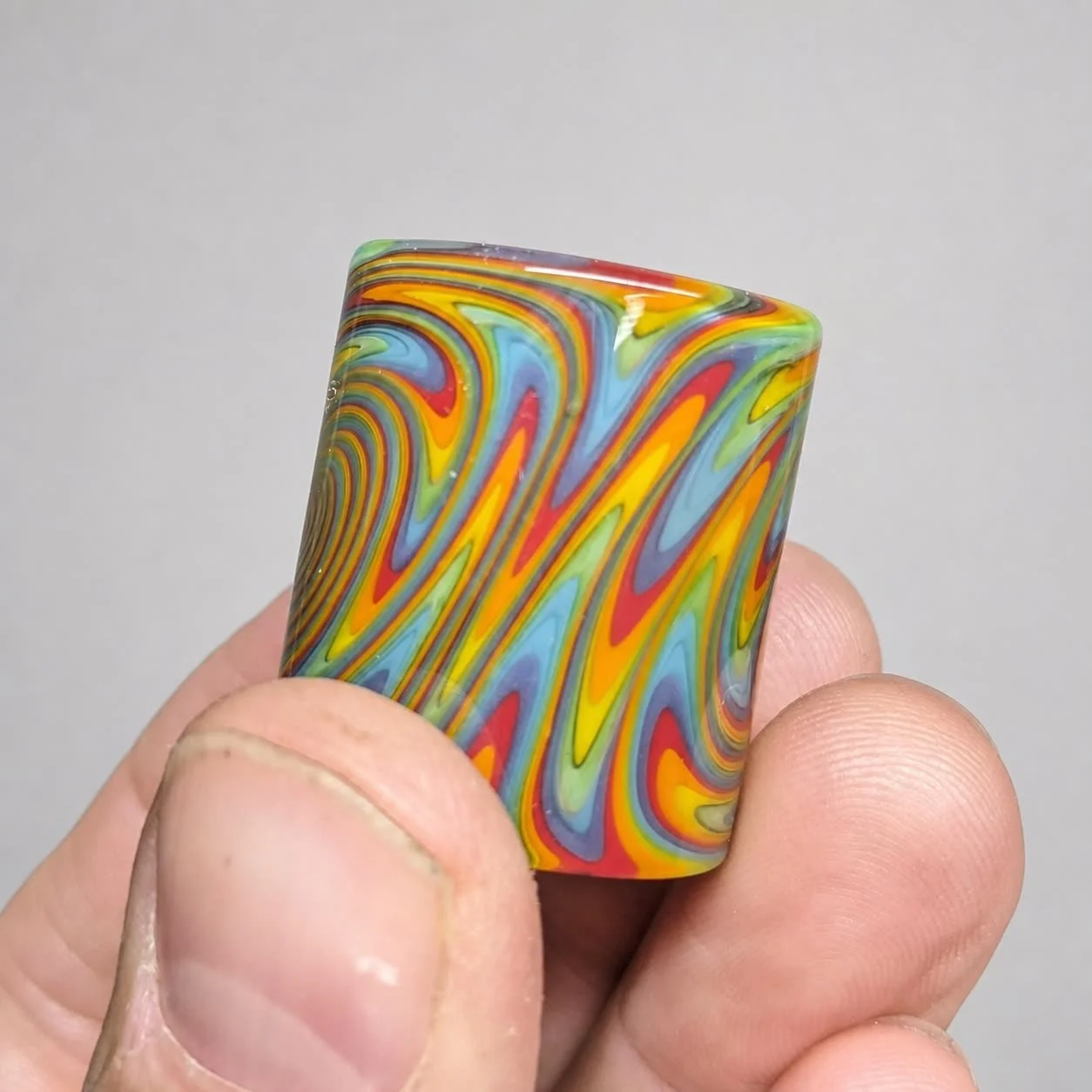 Side-pattern view of Tie Dye Spiral Mini glass guitar slide showing layered multicolor wig-wag lines