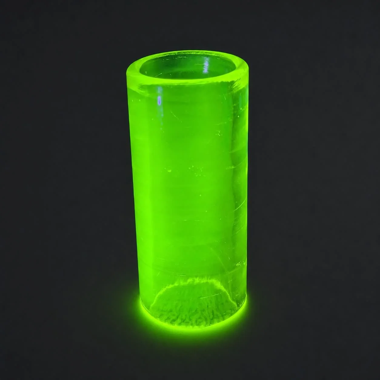 Blacklight Glow #2 glass guitar slide standing upright and glowing neon green under UV light