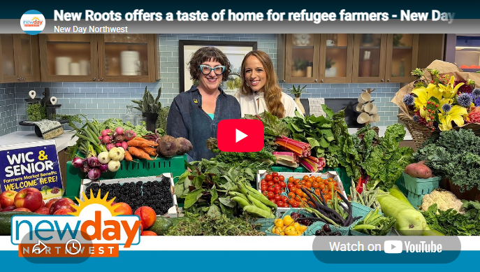 two women standing behind a display of fruits and vegetables