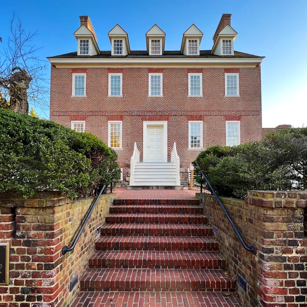 The house uses a header bond brick exterior with a full-height basement. The fieldstone foundation is embellished with “galleting”—small colored stones embedded in the mortar.