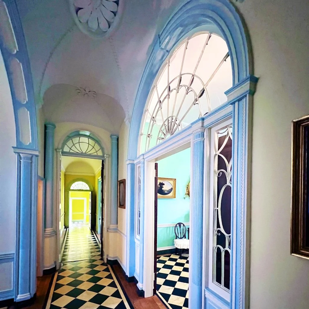 Homewood Central Hall: The halls are flanked by large rooms and bisected by a perpendicular east-west cross hall that also provides access to the hyphens and wings.