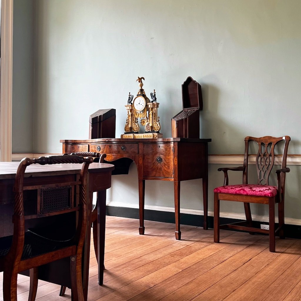 Formal Dining Room: The formal Dining Room at Woodlawn reflects the Federal interior trend of muted wall colors, minimal trim work painted white, and delicately carved or inlaid decoration.