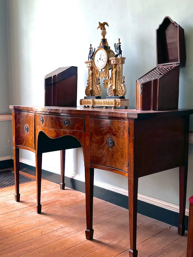 Formal Dining Room: French bronze and ormolu mantel clock with George III mahogany knife boxes on a Hepplewhite sideboard are displayed prominently in Woodlawn's formal dining room.