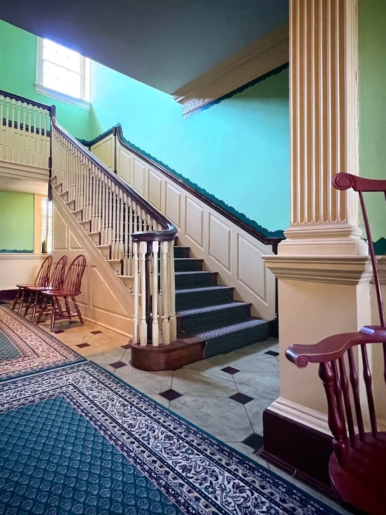 The center hall runs from front to back and is unobstructed by the stairway. The hall is adorned with a plaster entablature similar to that found at Mount Vernon.
