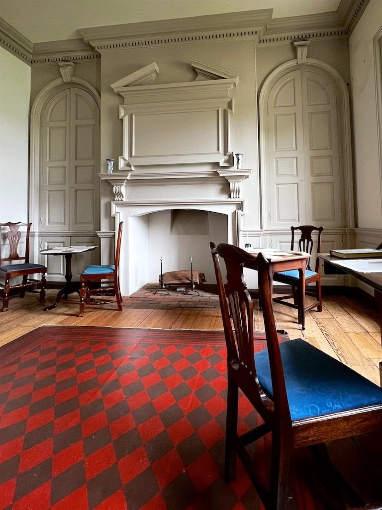 The little parlor was private and decorated plainly. The walls were painted a neutral grey. Above the fireplace is a split pediment overmantel. 