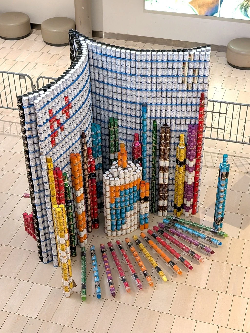 Cans stacked to create an art display of a school notebook with crayons and glue.
