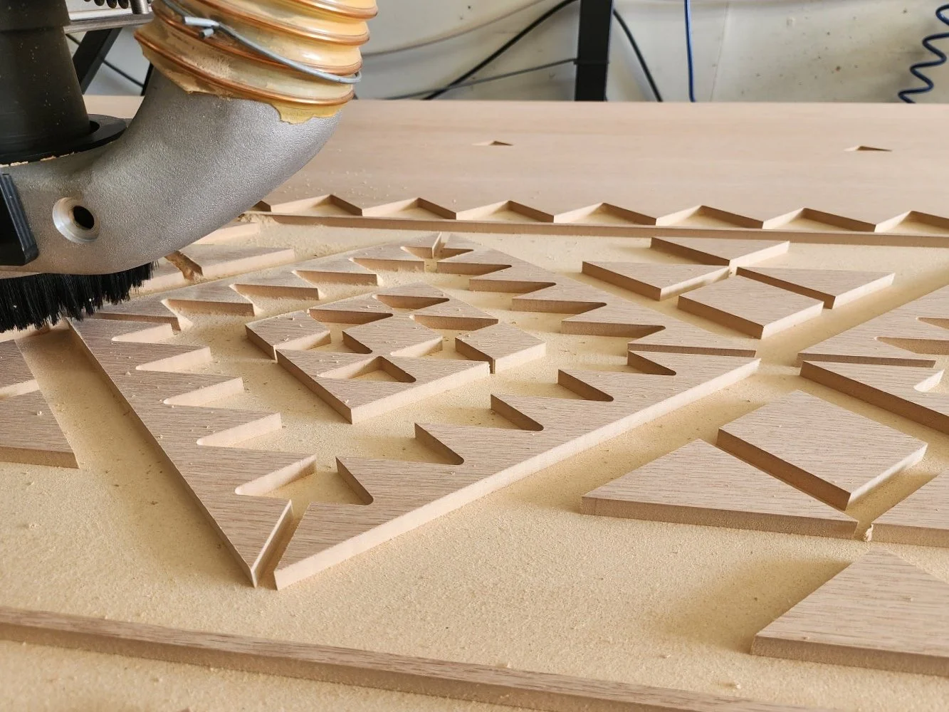 A close image of a geometric design being cut into a sheet of wood