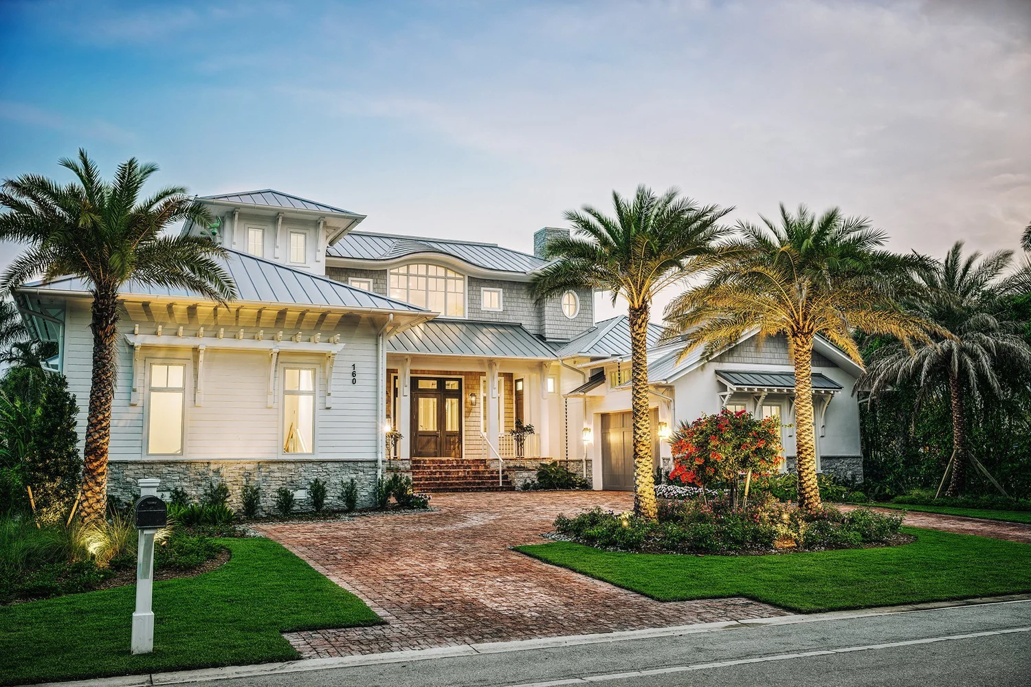 Coastal custom home exterior with palm trees at dusk in Naples, FL, built by Calusa Construction