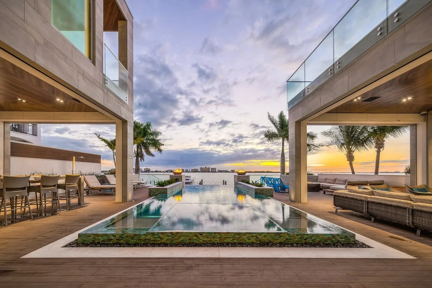 Infinity-edge pool and covered outdoor living overlooking the bay at sunset in Naples, FL