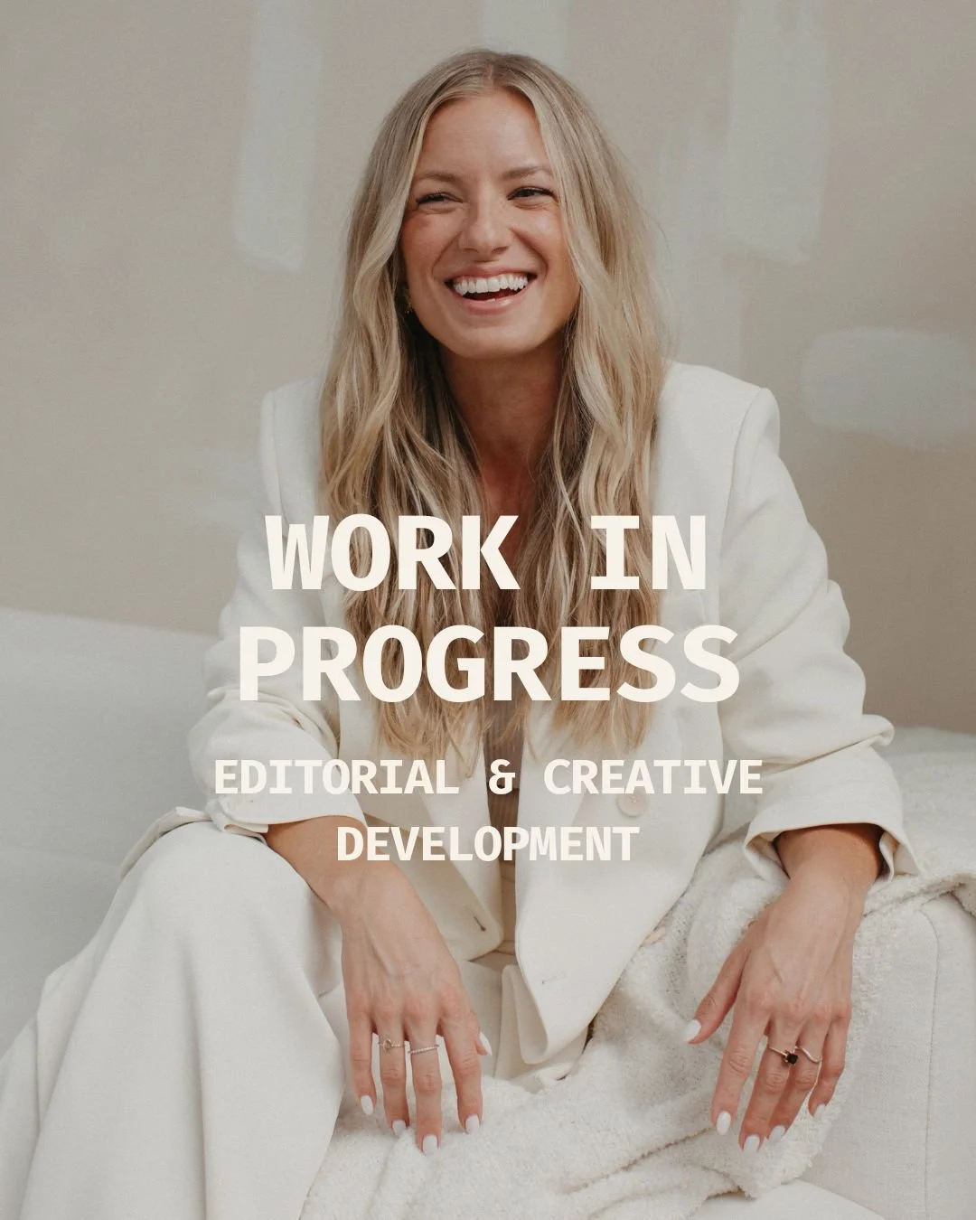 A woman in a white blazer sitting on a couch, smiling, with white text overlaid that reads 'Work in Progress, Editorial & Creative Development.'