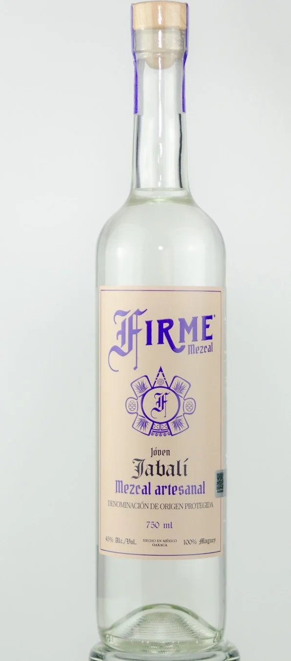 A clear glass bottle of Jabalí artisanal mezcal with a light purple and cream label featuring decorative designs and text indicating it's a young mezcal from Oaxaca, Mexico.