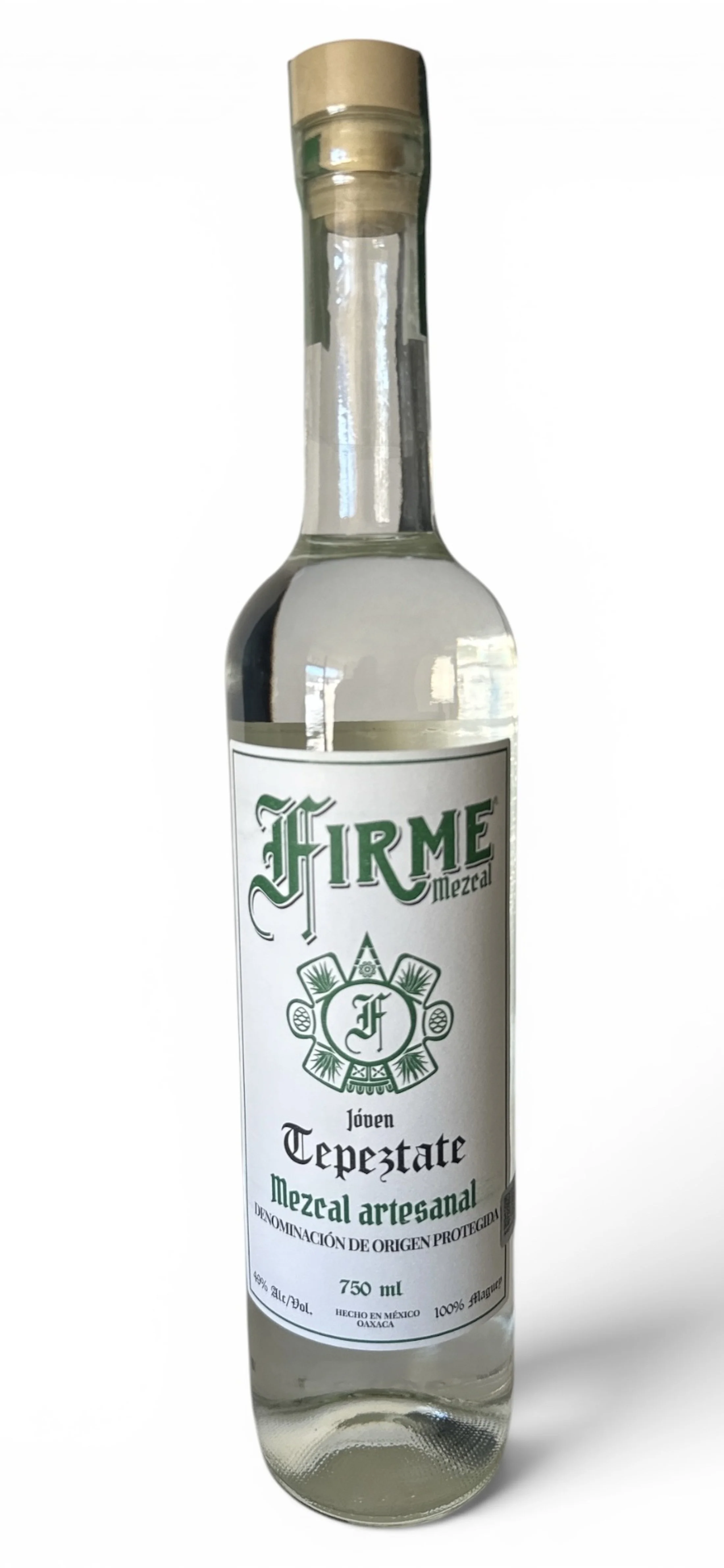 A clear glass bottle of Firme Jabalí artisanal mezcal with a beige label and purple text