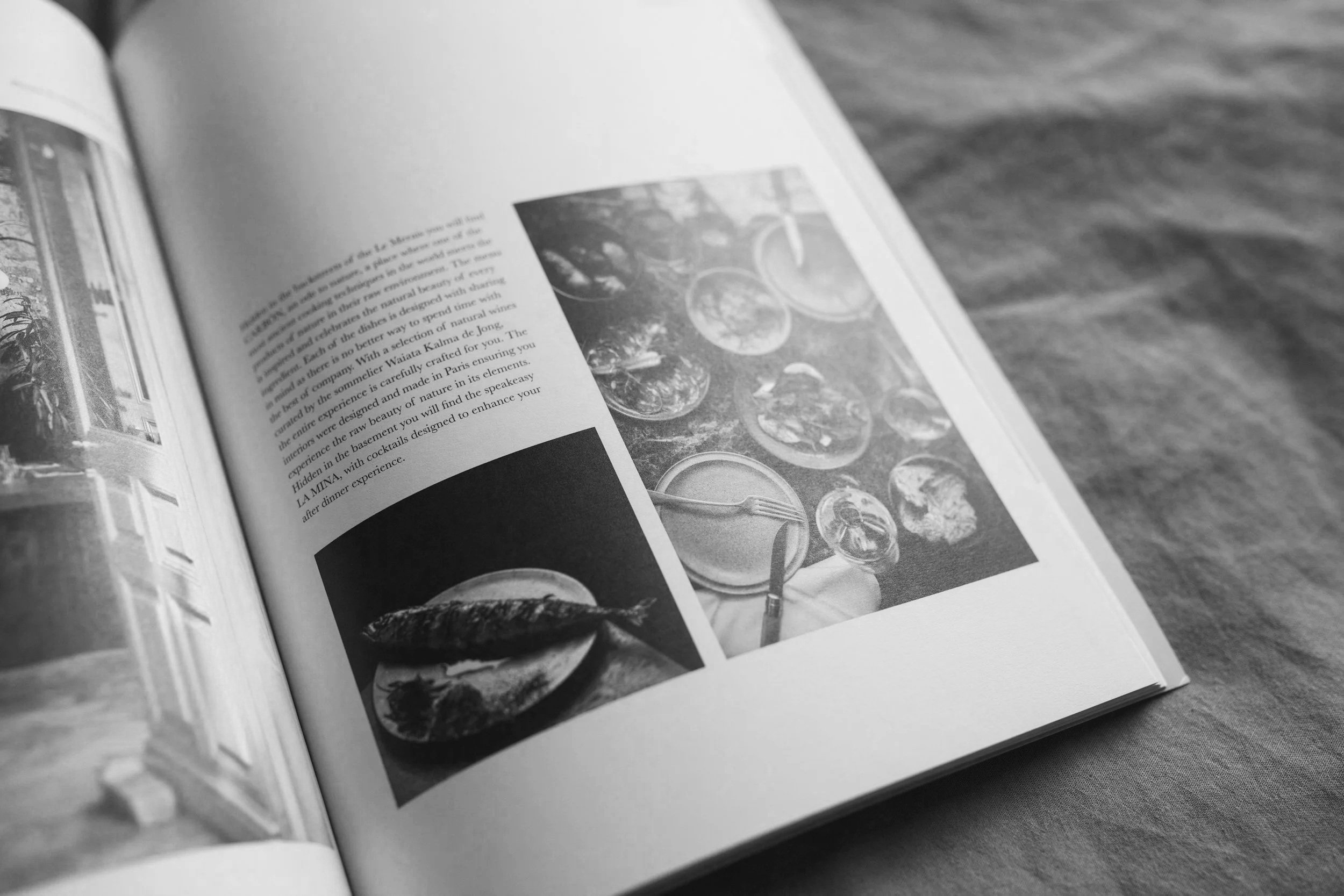 Open magazine featuring photos of a meal, including a plate with grilled fish and a table setting with plates, glasses, and cutlery.
