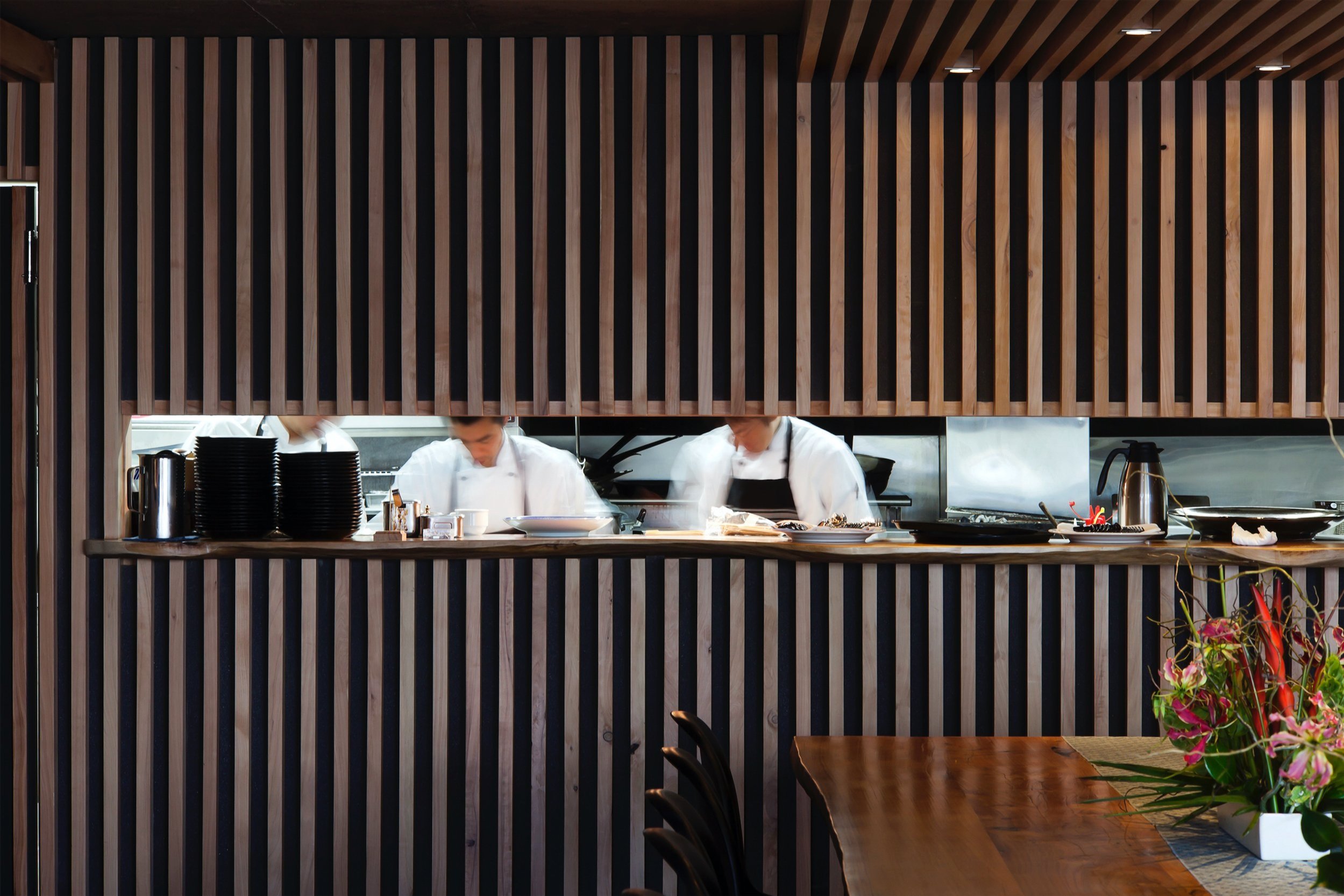 The chefs at work behind the counter, the pass lit under the batten screen