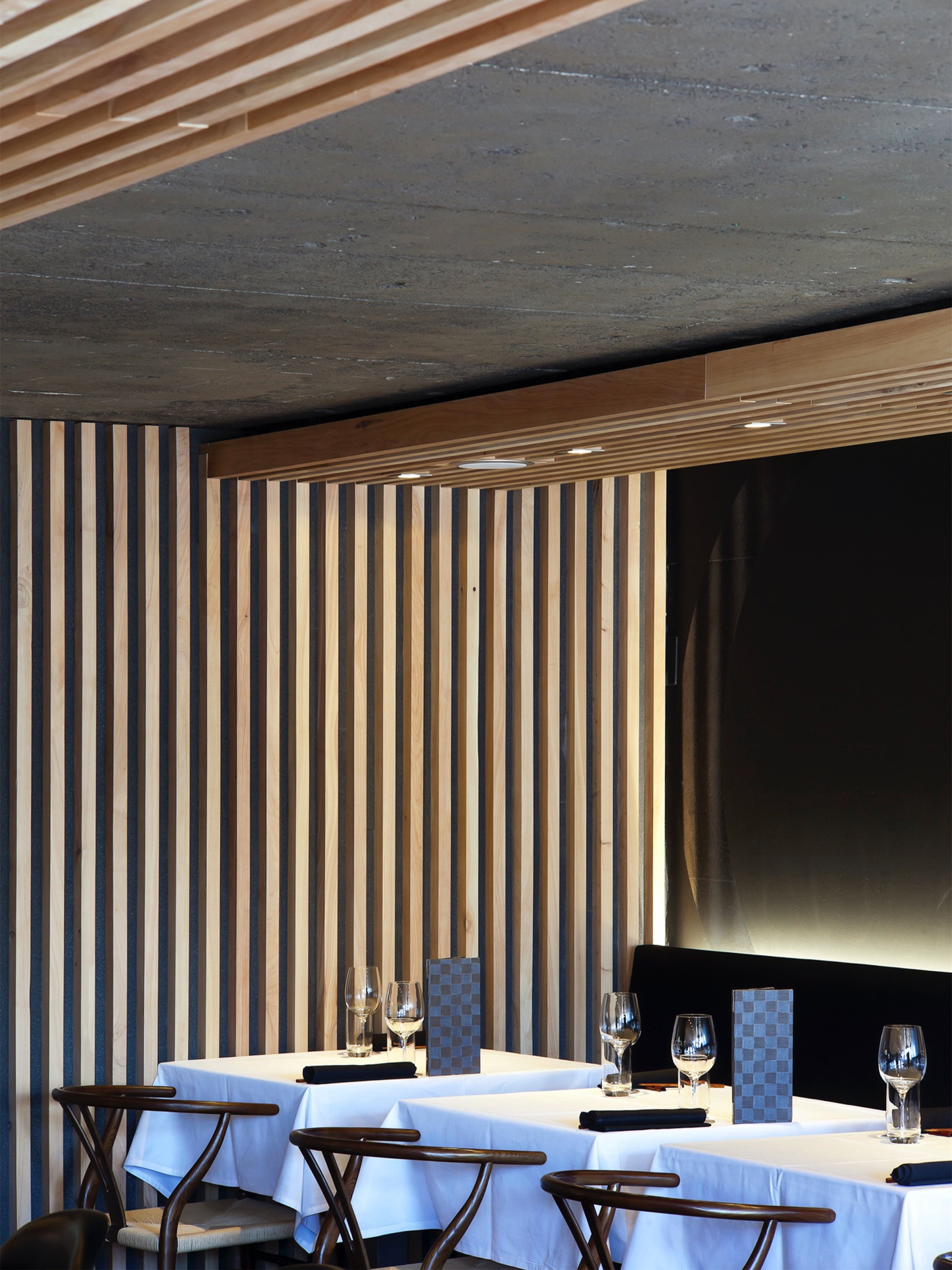 A corner table under the timber soffit, the batten screen carried past it