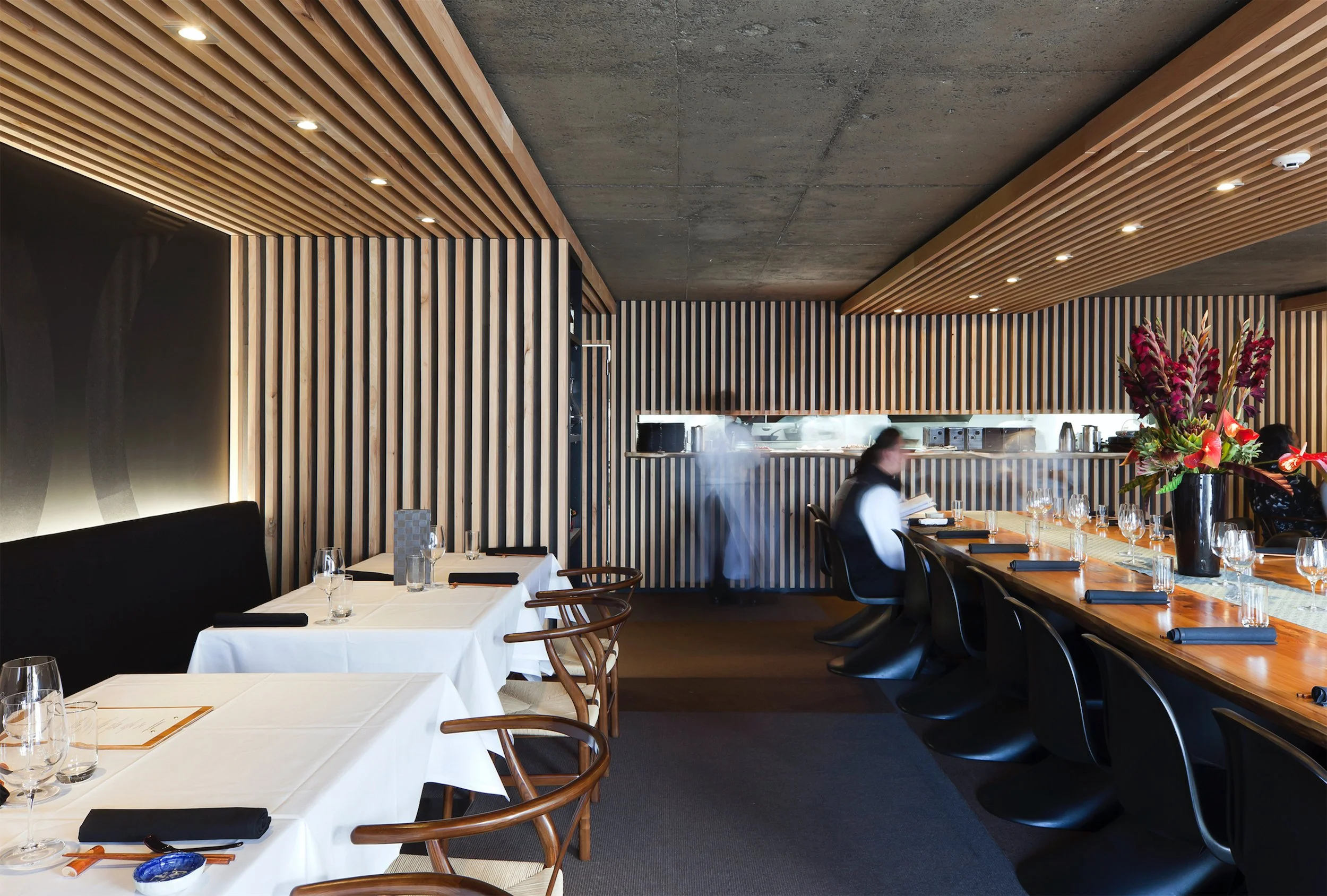 The dining room along the sushi counter, battens on one side and raw concrete above