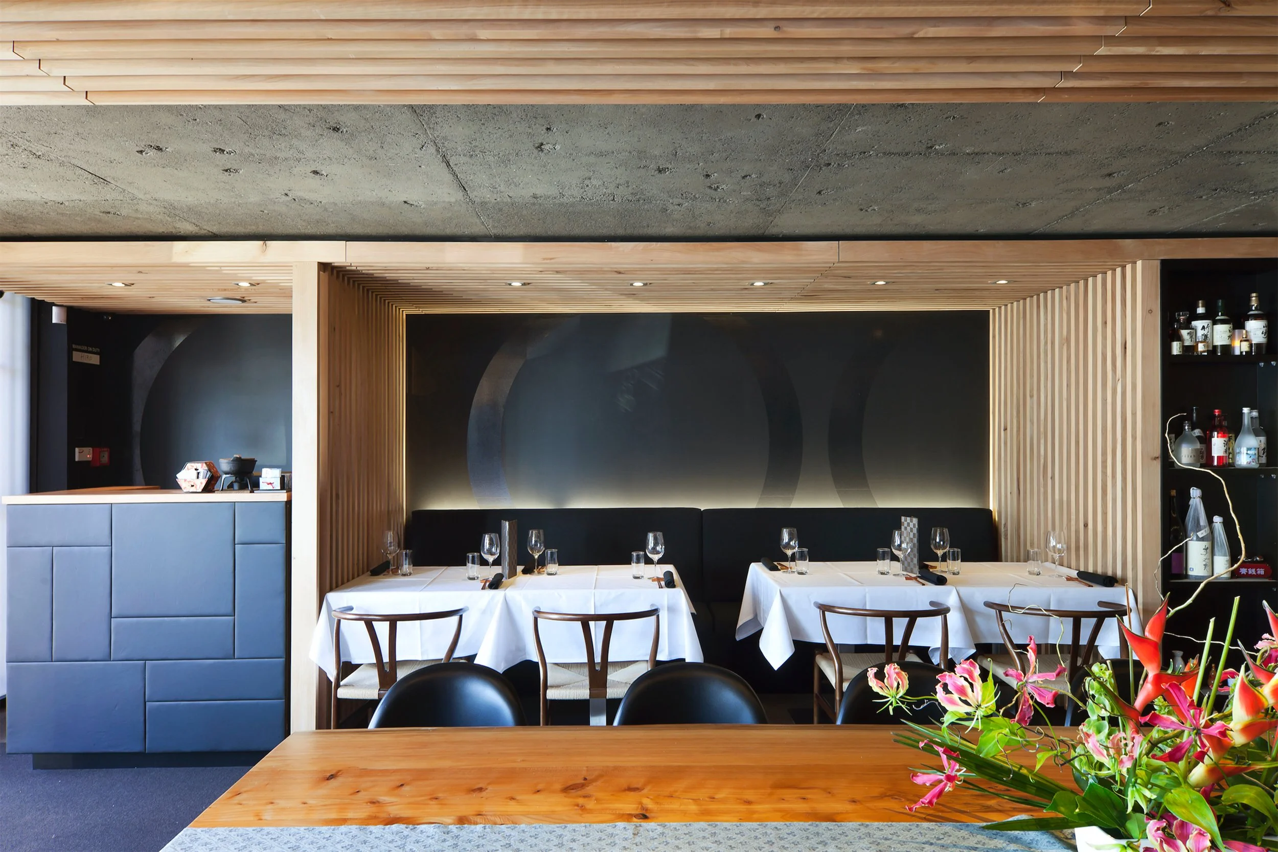 The room seen from the sushi counter, the dark panel behind the banquette