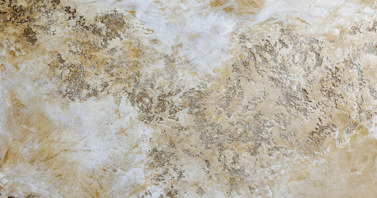 Close-up of a textured stone wall with beige, cream, and brown colors.