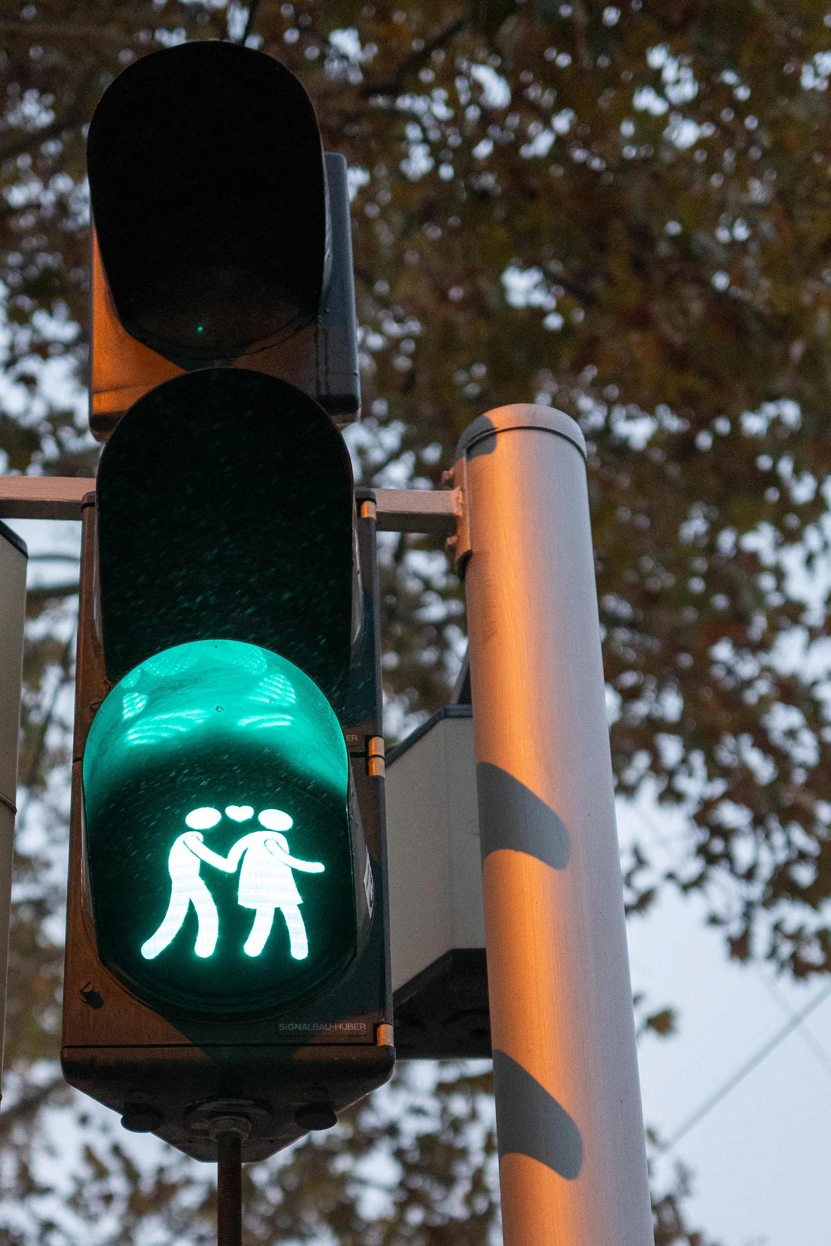 Feu de signalisation piétons avec un symbole de deux personnes se tenant la main, vert.