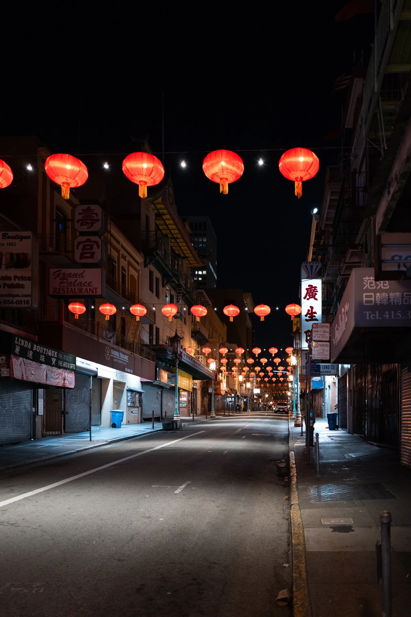 Rue vide dans un quartier asiatique la nuit, décorée de lanternes rouges suspendues au-dessus de la rue.