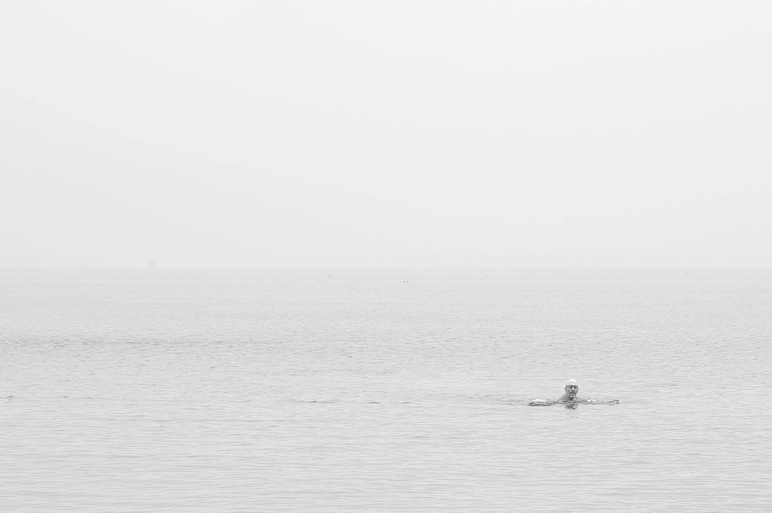 Une personne nageant seul dans une mer calme, paysage en noir et blanc.