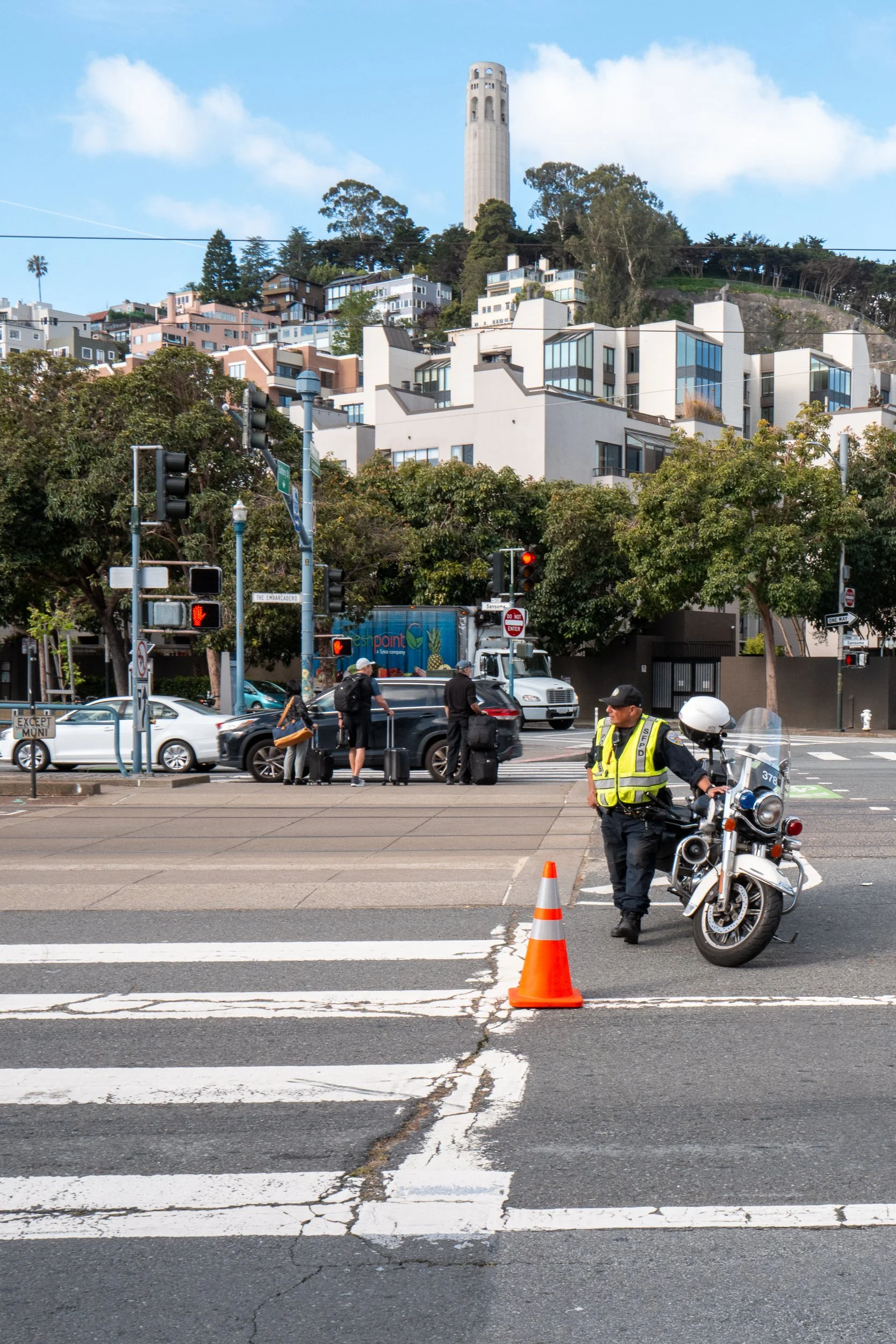 Agent de police à moto en uniforme avec cône de signalisation orange au croisement.