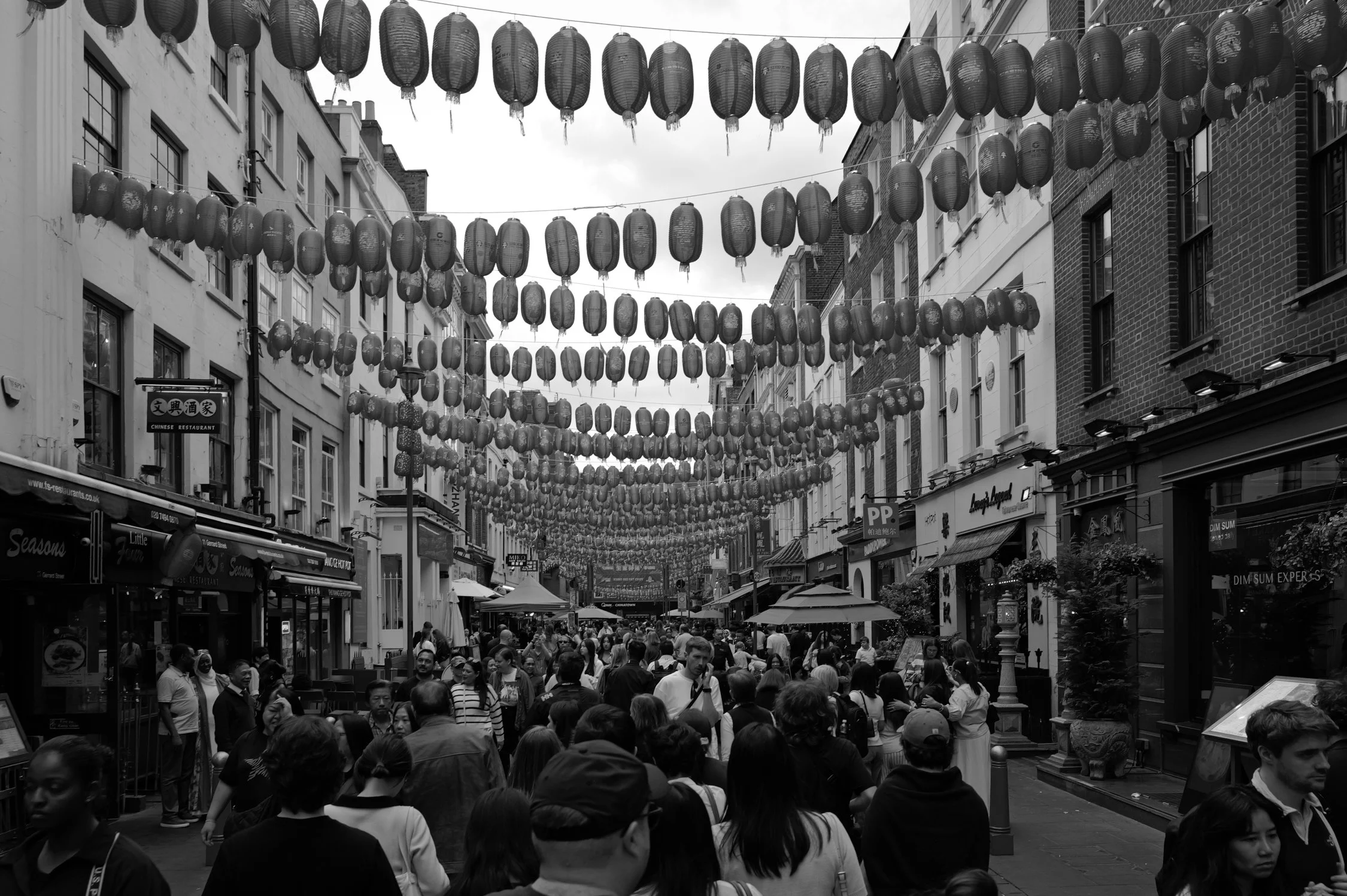 Une rue commerçante bondée avec des lanternes chinoises suspendues au-dessus de la rue