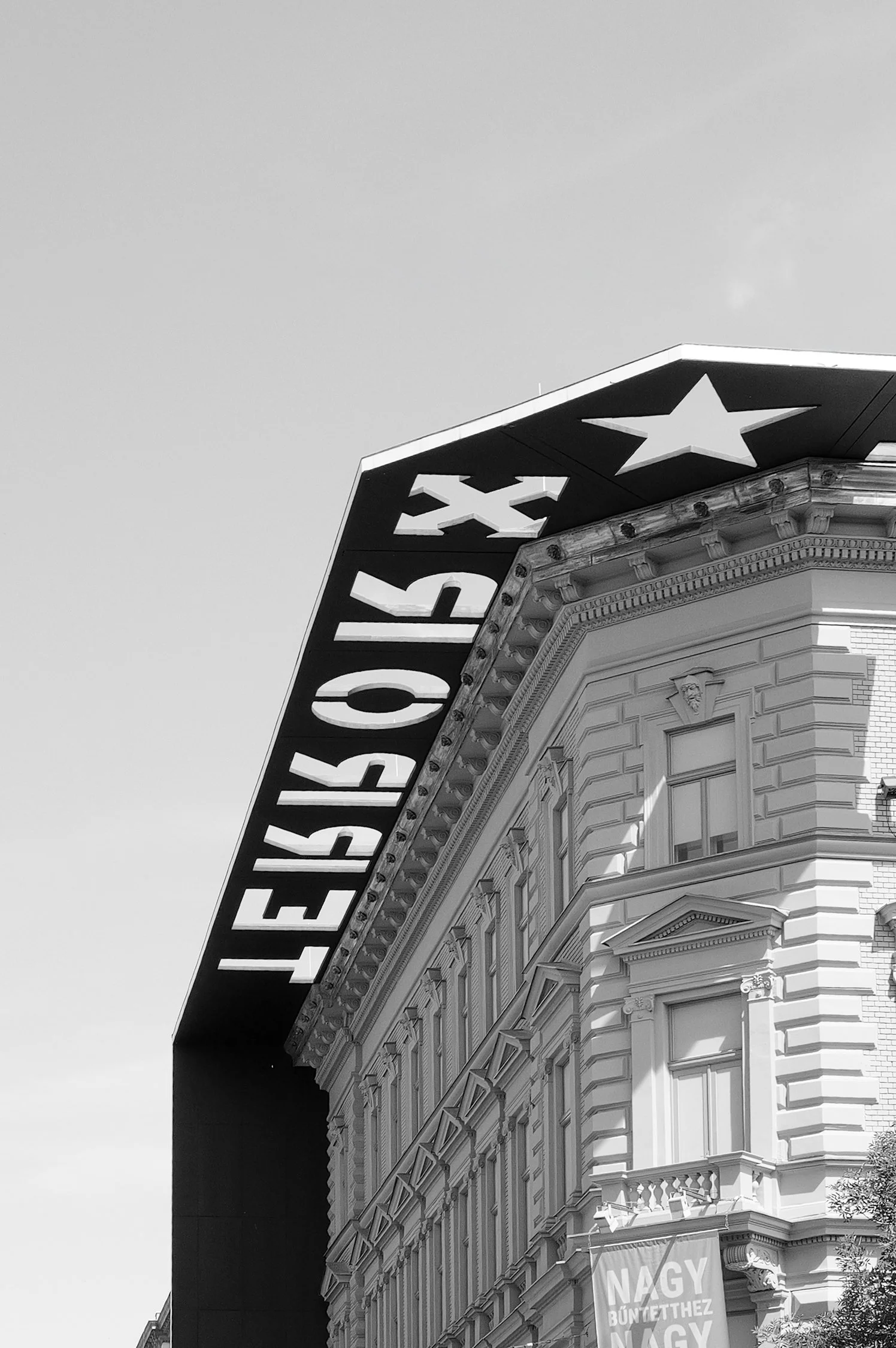 Une façade d'un bâtiment ancien avec une enseigne en néon indiquant 'Eruption' et un panneau promotionnel en dessous, en dehors d'un contexte urbain.