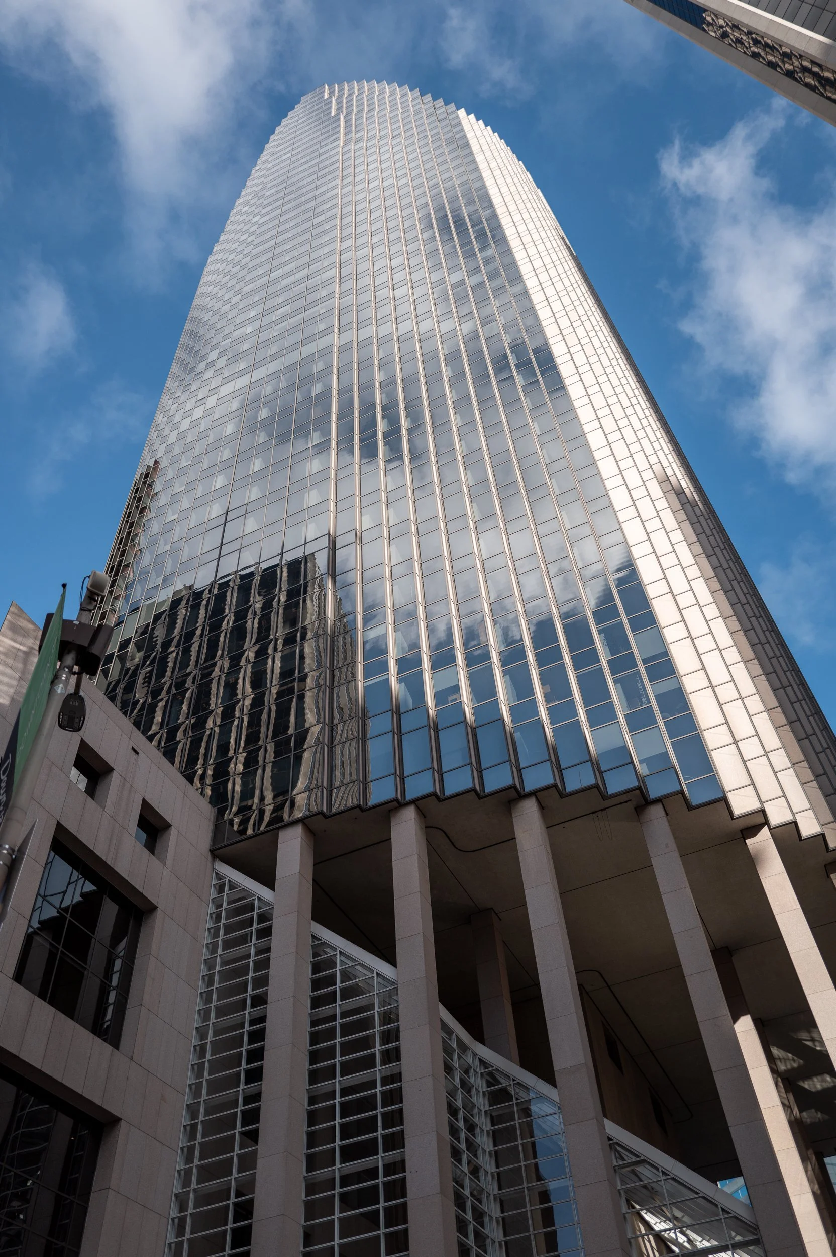 Gratte-ciel moderne avec beaucoup de fenêtres en verre réfléchissant le ciel et les nuages, vue en contre-plongée.
