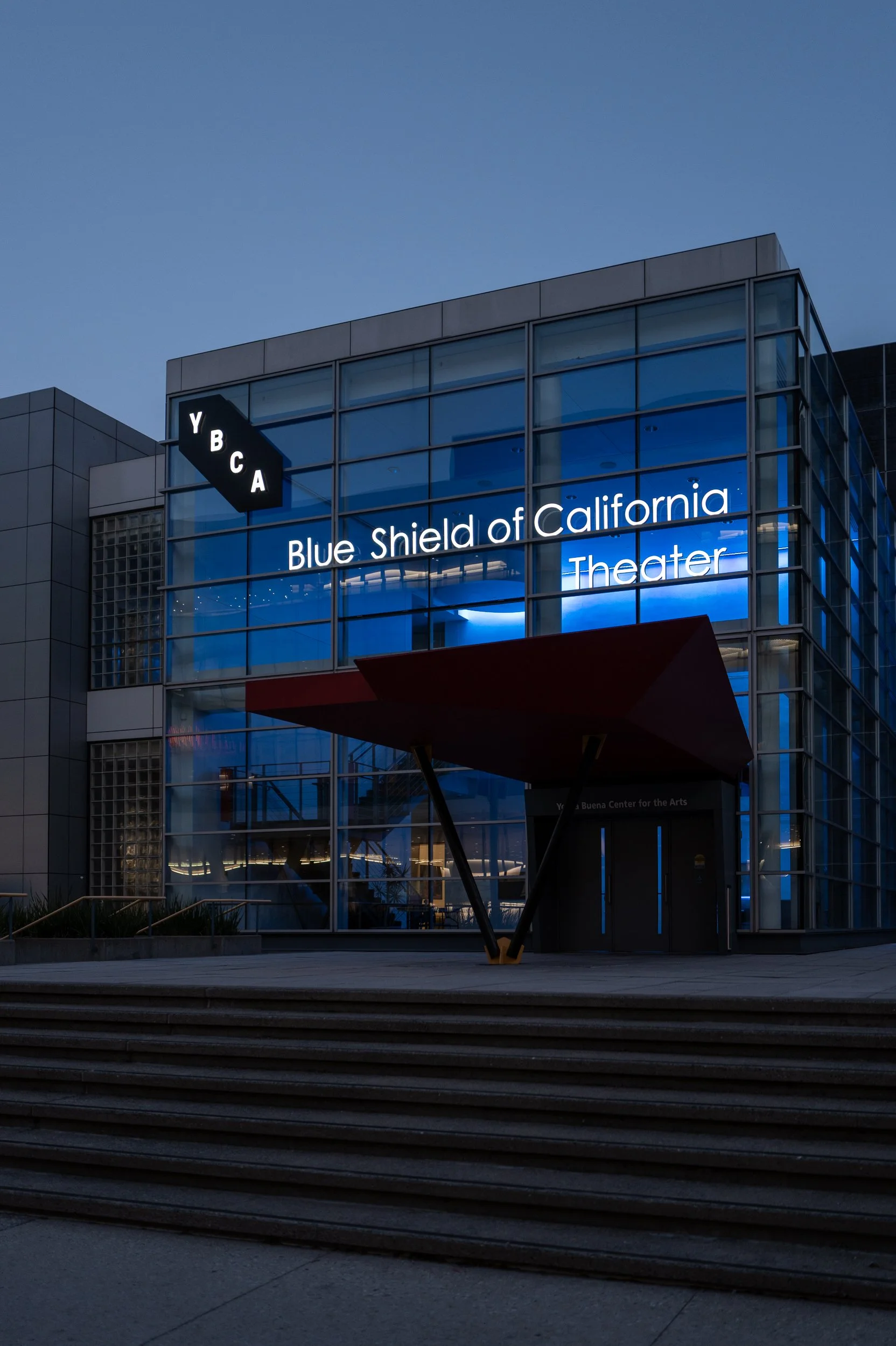 Vue extérieure du complexe Blue Shield of California Theater avec des fenêtres en verre et un panneau lumineux, étage en hauteur et escalier en bas.