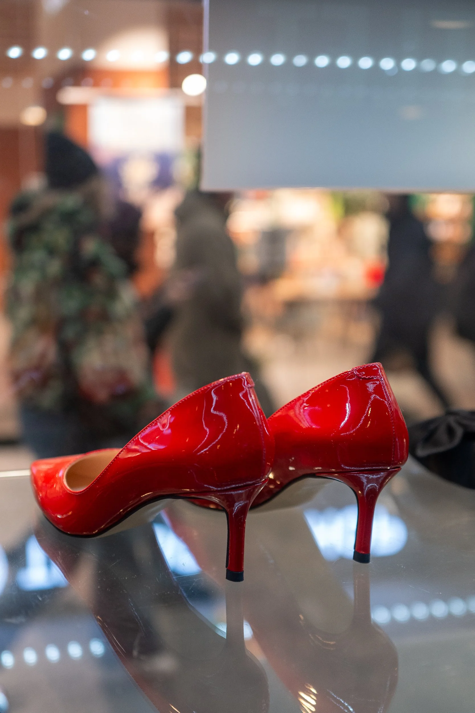 Chaussures à talons rouges en vitrine, avec des personnes floues en arrière-plan