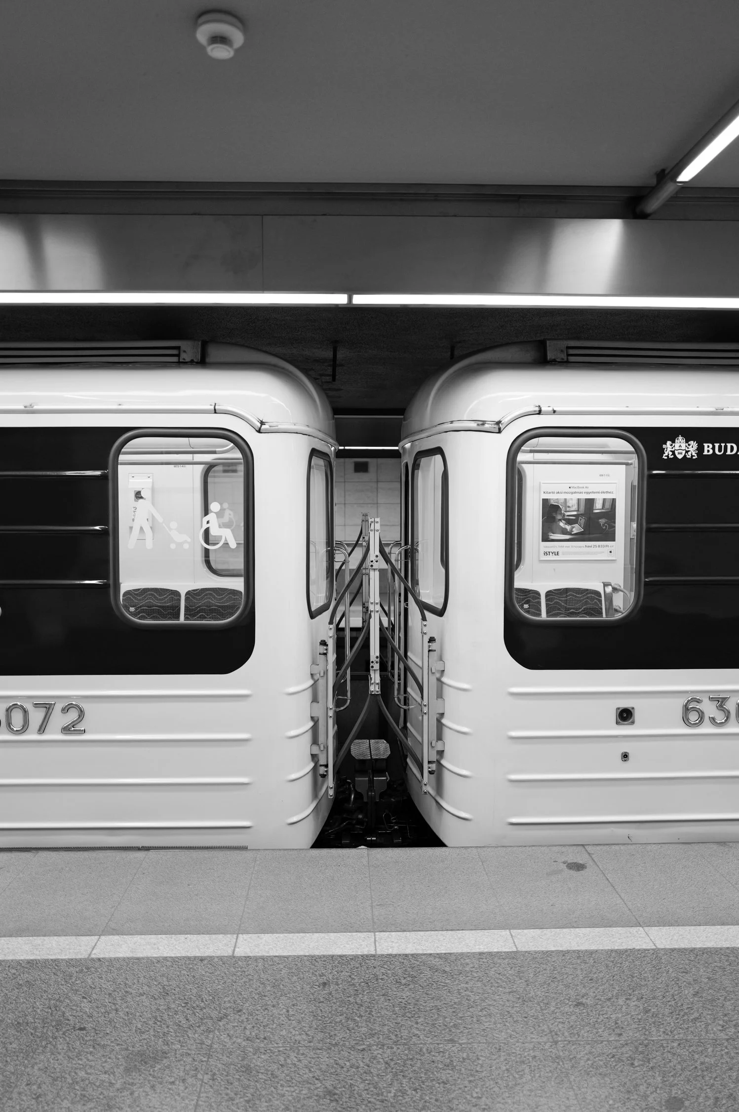Deux voitures de métro jumelées dans une station, vue frontale, en noir et blanc.