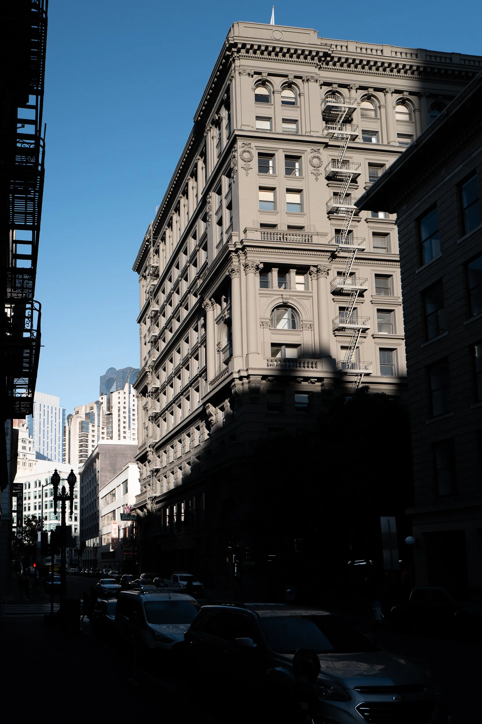 Un bâtiment historique dans une rue urbaine avec d'autres bâtiments modernes en arrière-plan, en plein jour.