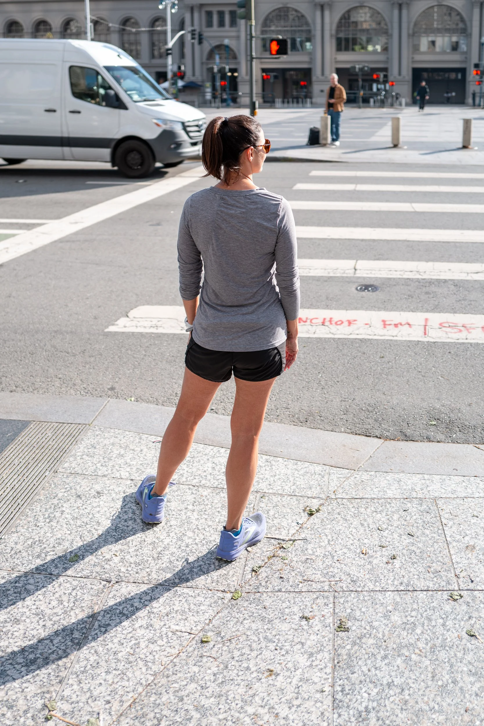 Femme en tenue de course regardant un passage piétons dans une ville