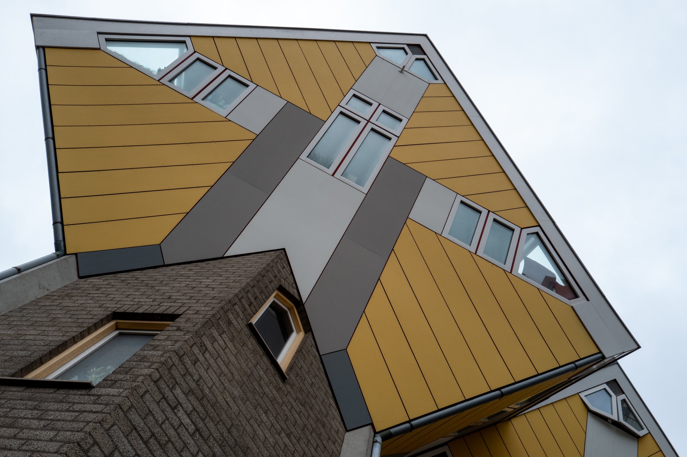 Un bâtiment moderne avec un design géométrique, utilisant des panneaux jaunes et gris, avec plusieurs fenêtres de forme inhabituelle.