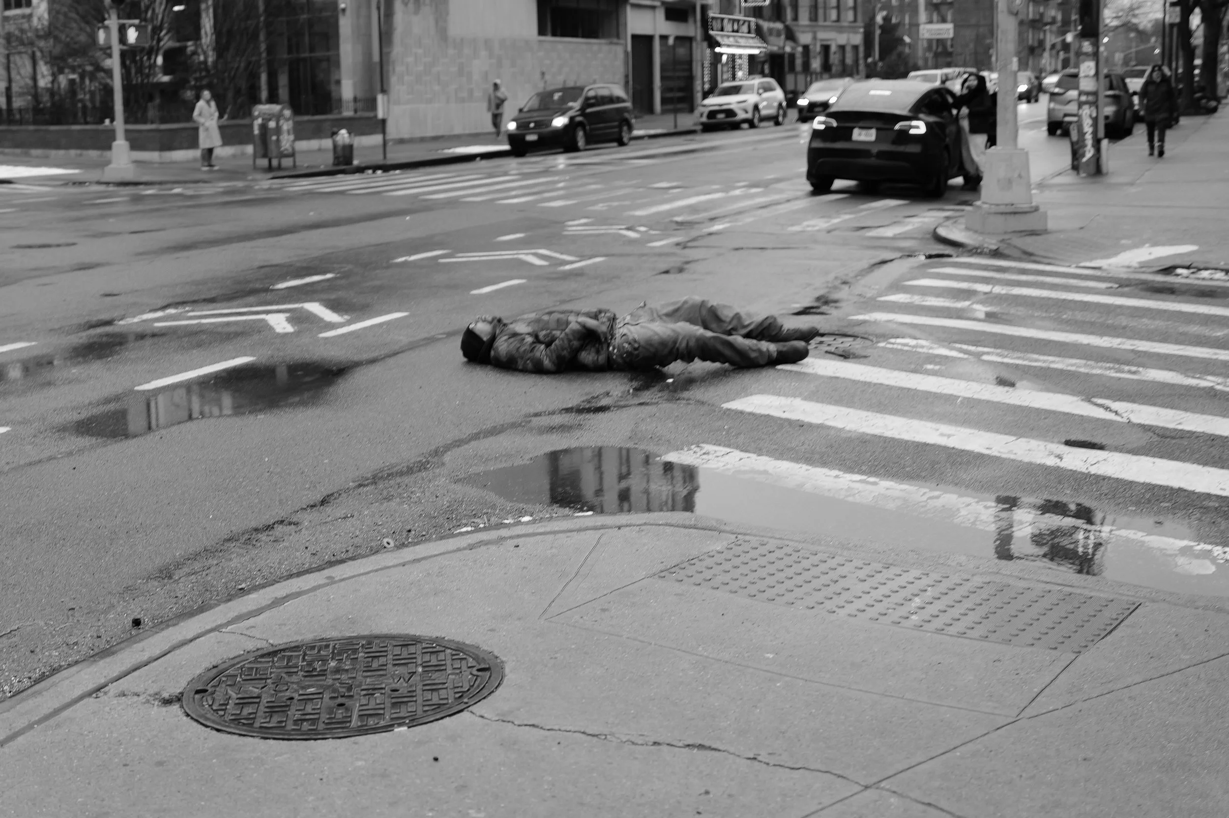 Une personne allongée sur un passage piéton, évoquant une situation dramatique dans une rue urbaine.