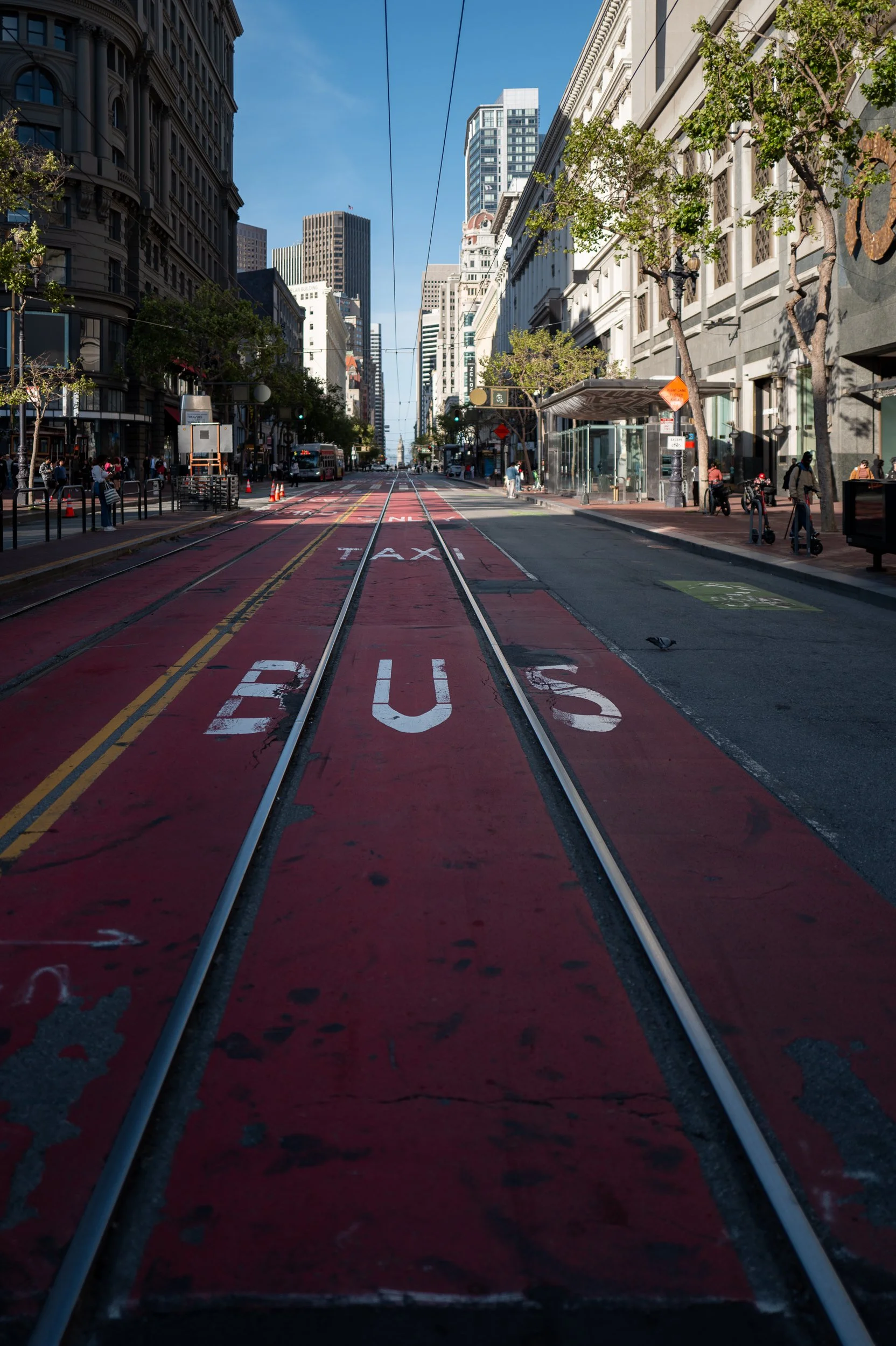 Rue en ville avec tramway, bâtiments de bureaux, piétons, arbres et ciel bleu