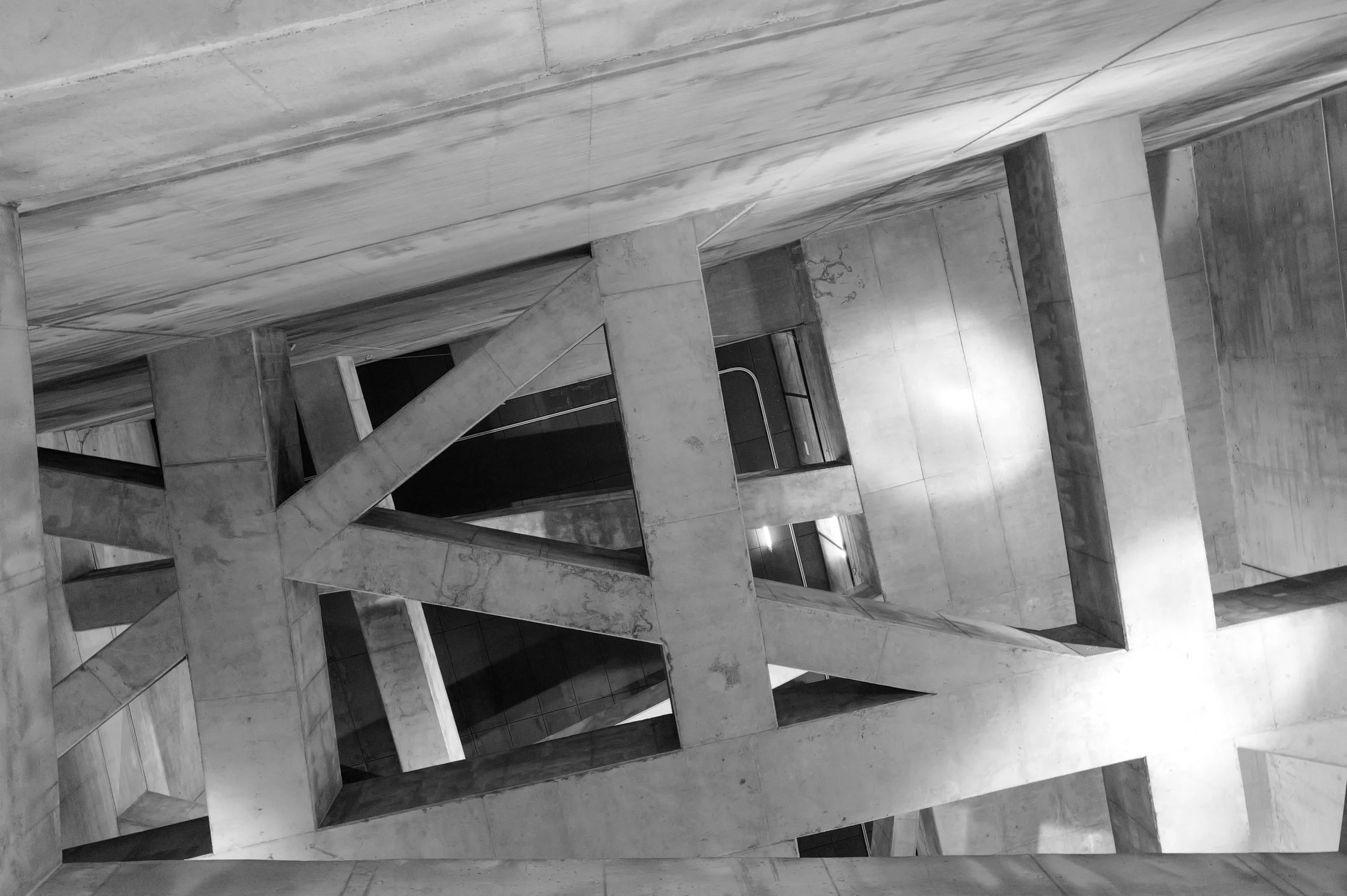 Photo d'une structure architecturale en béton avec des formes géométriques modernes et des escaliers. L'image est en noir et blanc.