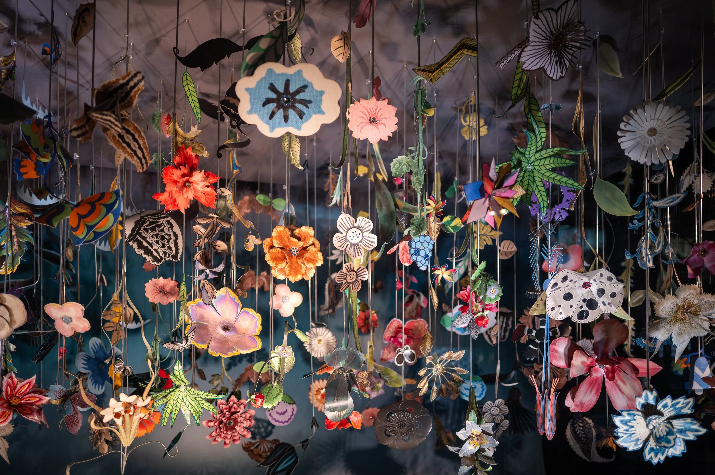 installation d'arts suspendus composés de fleurs et d'insectes en papier coloré avec un fond sombre